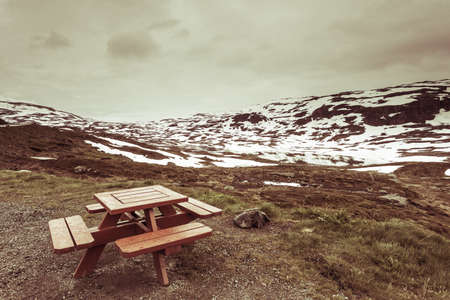 Picnic site wooden table and benches witn view at norwegian snowy mountains and lake, Scandynavia Europe.の写真素材