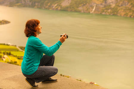 Tourism and travel. Woman tourist taking photo with camera, enjoying mountains fjords view in Sogn og Fjordane county. Norway Scandinavia.の写真素材