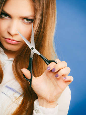 Haircare concept. Cutting and trimming. Young prefessional female barber hairstylist with scissors. Portrait of long haired girl prepared to styling hair.の写真素材