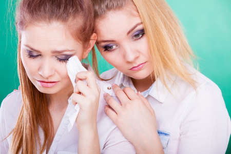 Young woman is sad crying and being consoled by friend. Girl comforting her sister. Mental problems depression and fatigue.の写真素材