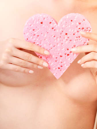 Skincare hygiene medicine and body treatment. Sensual naked woman with beautiful figure perfect skin holding pink heart shaped sponge in hands.の写真素材