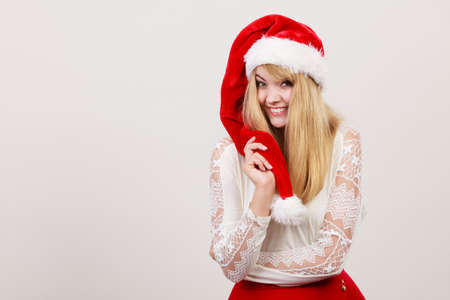 Happy smiling cute woman in santa helper hat. Pretty blonde girl in studio on gray. Christmas xmas season.の写真素材