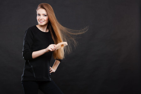 Preparation to evening party. Gorgeous attractive woman combing her long straight smoothy healthy hair before go out. Party and celebration concept.の写真素材