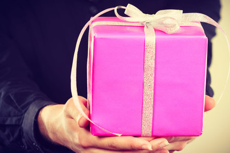 Celebration, holidays and happiness concept. Closeup of present pink gift box in male hands in hand