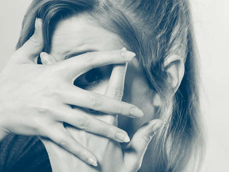 Attention shame observation psychology disorder concept. Shy girl hiding her face. Young blonde curious lady looking through her fingers while covering rest of head.の写真素材