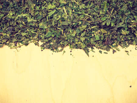 Healthy food, healing herbs, alternative herbal medicine concept. Border frame of dried herb nettle leaves on wooden board with copy spaceの写真素材