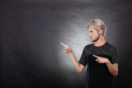 Young man angry thinking seeks a solution. Guy show right direction to decide and solve problems. Decision making process, doubt concept, studio shot on dark.の写真素材