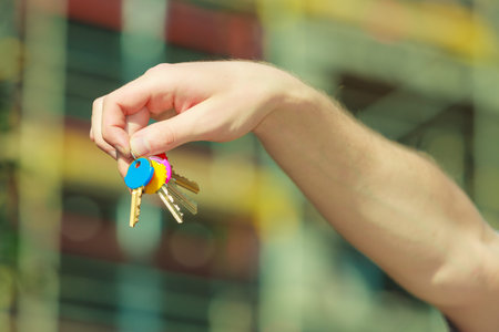 Closeup male hand holding keys in the house background