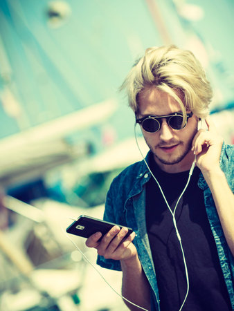 Vacation, relaxation, passion concept. Young fashionable blonde in sunglasses man relaxing,...
