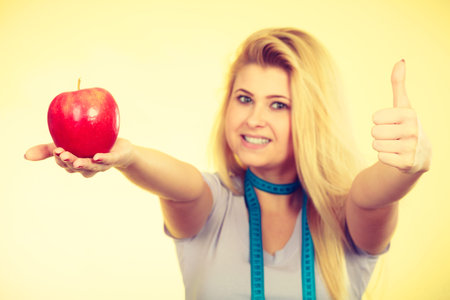 Diet, healthy lifestyle, organic food. Woman holding red apple showing thumb up gesture having...