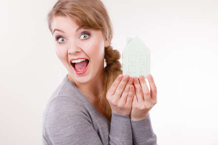 Housing property ownership family future finances concept. Smiling girl with home symbol. Young lady holding small house model.の写真素材