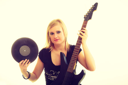 Music retro style. Young rock roll female star holds playing electric guitar surrounded by vinyl...