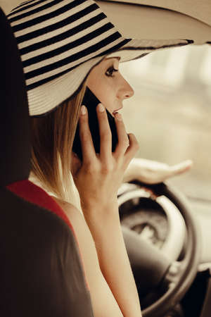 Distracted driver. Young attractive woman using mobile phone, talking while driving the car.の写真素材