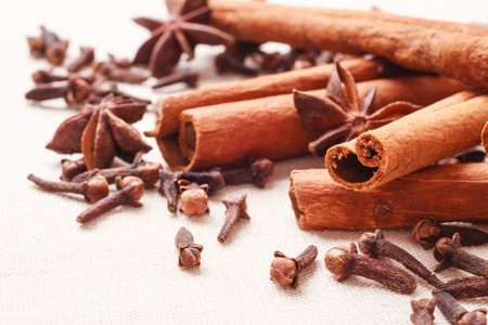 Spices for christmas cakes cinnamon sticks anise stars and cloves on burlap background