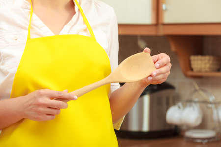 Cooking and preparing food meal concept. Part body woman chef cook housewife holding ladle spoon in kitchen.の写真素材