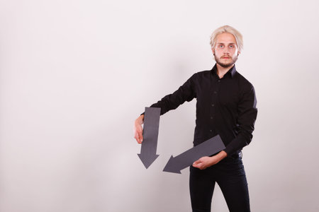 Planning, directions, choices concept. Man holding two black arrows pointing in the same directions...