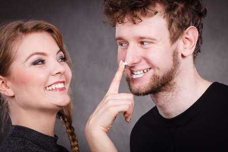 Fun and joy. Healthcare and protection. Funny smiling couple playing with moisturizer cream. Lovely woman with charming man.の写真素材