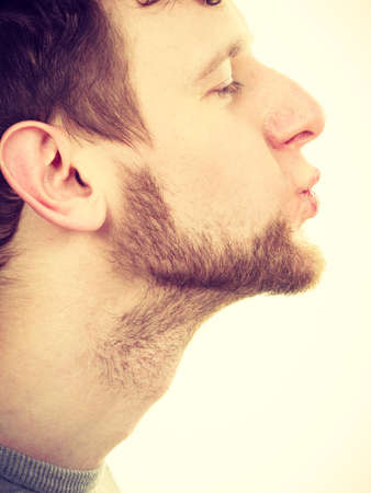 Young bearded handsome man blowing kiss, side view closeupの写真素材
