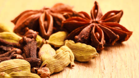 Spices for christmas cakes cardamom anise stars and cloves on wooden table surfaceの写真素材