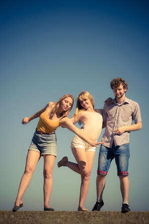 Friendship happiness summer holidays concept. Group of friends boy two girls having fun outdoor stretching arms celebratingの写真素材