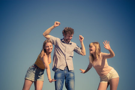 Friendship freedom summer holidays concept. Group of friends boy two girls spending time together having fun against skyの写真素材
