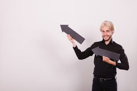 Planning, directions, choices concept. Man holding two black arrows pointing in the same directions....
