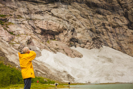 Tourism vacation and travel. Male tourist taking photo with camera, enjoying mountains landscape, Norway Scandinavia.の写真素材
