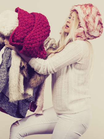 Woman in furry hat holding heavy clothes pile. Picking winter clothing concept.の写真素材