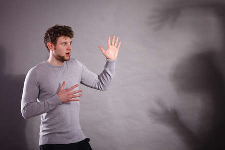 Violence against man. Scared afraid man portrait. Negative relations in partnership. Expressive young male in dramatic situation.の写真素材