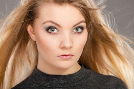 Haircare, beauty, hairstyling concept. Closeup portrait of young attractive blonde woman wearing dark t shirt having windblown beautiful long hair.の写真素材