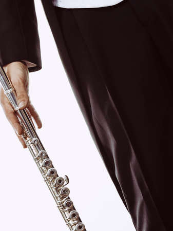 Classical music study concept. Male flutist musician performer with flute. Young elegant man wearing tailcoat holds instrument, part of bodyの写真素材