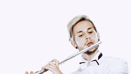 Flute music playing professional male flutist musician performer. Young elegant stylish man with instrumentの写真素材