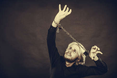 No freedom, social problems concept. Furious man with chained hands, studio shot on dark grunge backgroundの写真素材