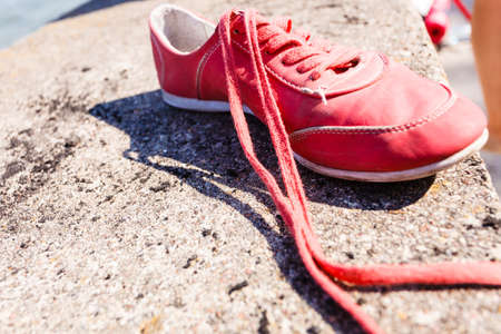 Travel holidays hiking walking symbol. Empty shoe on wall. Piece of footwear lying next to sea.の写真素材
