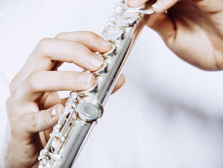 Hands of young man playing the flute. Male flutist musician performer holding instrument, close upの写真素材