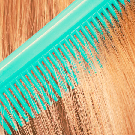 Combing and brushing concept. Routine everyday hygiene. Close up of detail green comb in red smoothy...