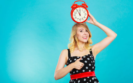 Management time concept. Blonde fashion girl wearing black dotted dress smiling face expression with...