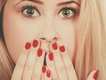 Expressions, gestures concept. Portrait of shocked, amazed attractive woman covering her mouth with hands showing red nailsの写真素材
