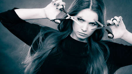 Style and fashion. Professional hairstylist barber with new idea of look changing. Long haired woman with scissors creating hairdo coiffure.の写真素材