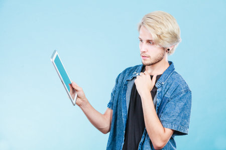 Education social media. Modern technology internet concept. Stylish handsome young man using tablet computer, thinkingの写真素材