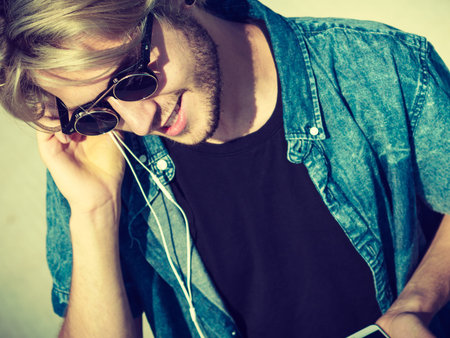 Vacation, relaxation, passion concept. Young fashionable blonde in sunglasses man relaxing,...