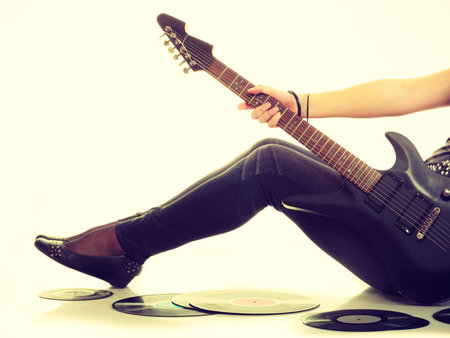 Music retro style. Young rock roll female star holds playing electric guitar surrounded by vinyl...