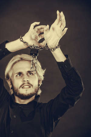 No freedom, social problems concept. Furious man with chained hands, studio shot on dark grunge backgroundの写真素材