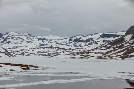 Norway hiking area, scenic mountains landscape, hills and frozen lakeの写真素材