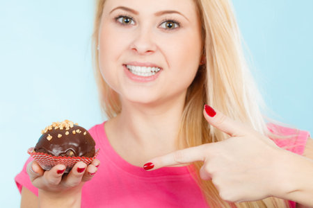 Diet, sweets, food concept. Woman holding delicious chocolate cupcake with peanut frosting about to...