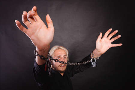 No freedom, social problems concept. Furious man with chained hands, studio shot on dark grunge backgroundの写真素材