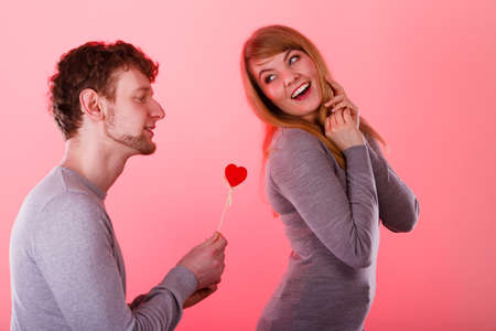 Romance symbolism valentines concept. Man giving heart to his girl. Young male proffesing love to woman, by giving her heart.の写真素材