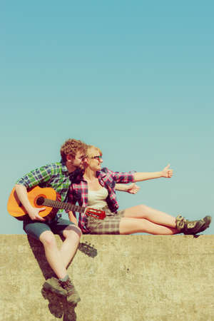 Young man playing guitar to his girlfriend outdoor sunny summer day sky background - dating romantic coupleの写真素材