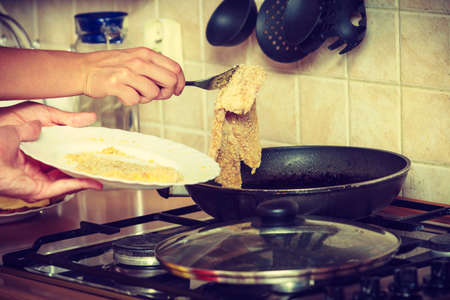 Human frying breaded chicken cutlet on fry pan. Person making dinner meal.の写真素材