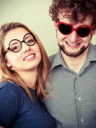 Happy young man in heart shaped glasses and woman. Smiling friends couple in studio.の写真素材